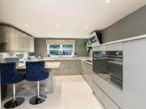 una cocina con armarios blancos y sillas azules en 4 Woodland Park, en Bideford