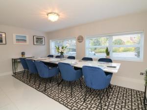 a dining room with a long table and blue chairs at 4 Woodland Park in Bideford