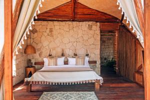 1 dormitorio con 1 cama en una pared de piedra en Ikal Tulum Hotel en Tulum