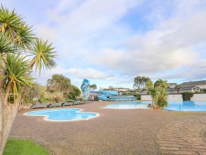 una piscina resort con palmeras y un tobogán en The Warren U5 en Abersoch