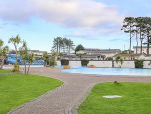 a swimming pool in a park with trees and grass at The Warren U5 in Abersoch