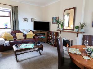 a living room with a couch and a tv and a table at Amber Cottage in Matlock