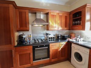 a kitchen with wooden cabinets and a stove top oven at Amber Cottage in Matlock