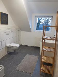 La salle de bains est pourvue de toilettes, d'un lavabo et d'une fenêtre. dans l'établissement Monteurwohnung in Wesermarsch, Küche, Einzelbetten, Stedinger Landhotel, à Berne