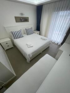 a white bedroom with a bed and a window at Dalyan Risus Suite in Çeşme