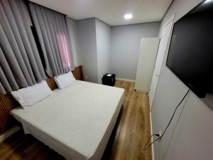 um pequeno quarto com uma cama e uma televisão de ecrã plano em Pousada Al Mare em Balneário Camboriú