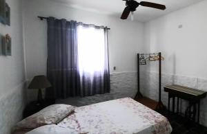 a bedroom with a bed and a window and a fan at PousadaRecanto684Guarujá in Guarujá