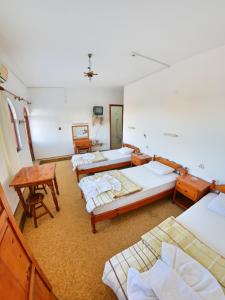 a room with three beds and a table and chairs at Murat Hotel in Demre