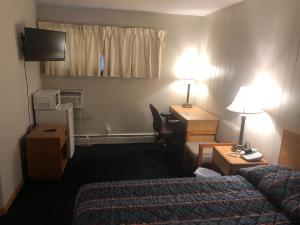 een hotelkamer met een slaapkamer met een bed en een bureau bij Parkway Motel in Neenah