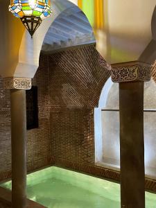 uma piscina de água num edifício com tecto de vitrais em Riad Alena em Marraquexe