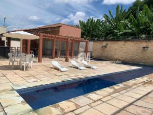 ein Haus mit einem Pool mit Stühlen und einem Sonnenschirm in der Unterkunft Ap Completo na zona Nobre com 3 quartos, sendo 1 suíte in Teresina
