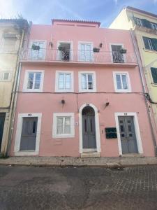 a pink building with windows and a balcony at Casas do Olival Apartments in Lisbon