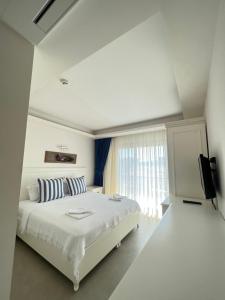 a white bedroom with a bed and a television at Dalyan Risus Suite in Çeşme