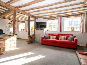 un sofá rojo en una sala de estar con ventanas en 1 Northside Cottages en Godalming
