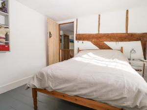 a bedroom with a large bed with a wooden headboard at 1 Northside Cottages in Godalming