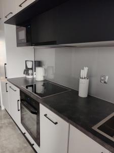 a kitchen with white cabinets and a black counter top at Apartament Manhattan in Ełk