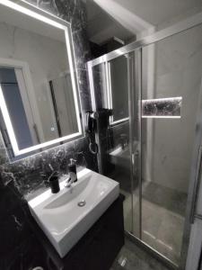 ein Bad mit einem Waschbecken, einer Dusche und einem Spiegel in der Unterkunft Apartament Manhattan in Lyck
