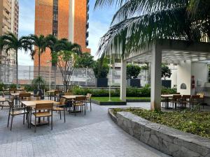 un patio con mesas, sillas y palmeras en Apartamento prox a Beira Mar, en Fortaleza