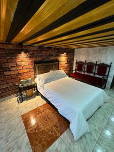 a large bed in a room with a brick wall at Habitación con baño privado en aparthotel in Manizales