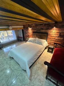 1 dormitorio con 1 cama grande y pared de ladrillo en Habitación con baño privado en aparthotel en Manizales