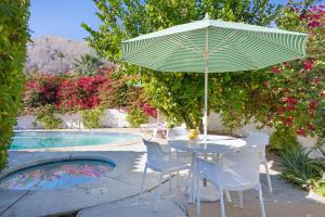 a table and chairs with an umbrella next to a pool at Hacienda Salida in Palm Springs