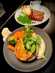 a plate of food with vegetables and meat on a table at The White House at The Tinners Arms in St Ives