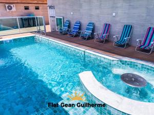 a swimming pool with chairs in a building at Flat Gean Guilherme - Canasvieiras in Florianópolis