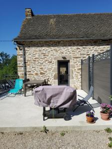 eine Terrasse mit einem Tisch und Stühlen sowie ein Gebäude in der Unterkunft Gîte avec piscine intérieure in Moyrazès