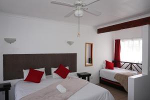 a bedroom with two beds with red pillows at Sheba Rock Guesthouse in Nelspruit +79 photos