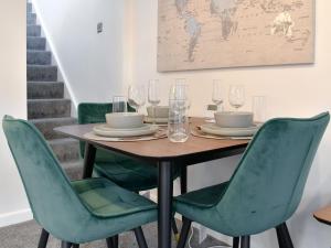 a dining room table with green chairs and wine glasses at Deleur House in Great Malvern