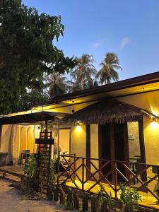 a building with a straw hut with palm trees at Huvan Inn in Fulidhoo