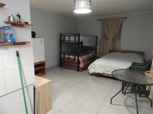 a room with a bed and a table and a refrigerator at Hostal Ribera de Quitor in San Pedro de Atacama