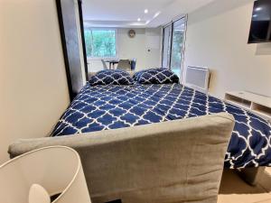 una camera da letto con un grande letto e un piumone blu di Le Petit Rocher 30m2- Studio standing tout confort a Saint-Aignan-Grand-Lieu