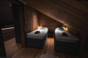 two beds in a room with wooden walls at Le-Villa Black in Levi