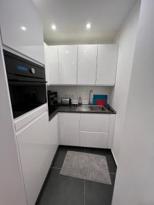 eine kleine Küche mit weißen Schränken und einem Waschbecken in der Unterkunft Lovely Apartment close to the Heart of Nürnberg in Nürnberg