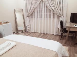 una camera con letto, specchio e scrivania di Rehoboth Guesthouse a Durban