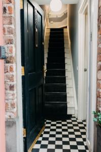 a hallway with a black door and black and white checkered floor at Belfast City self catering 3 bedroom town house in Belfast