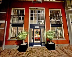 um edifício vermelho com dois vasos de árvores em frente a uma porta em Atelier Raamwerk City Apartments Deventer 125m2! em Deventer