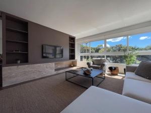 sala de estar con sofá blanco y TV en Apartamentos Altos da Bela Vista by Achei Gramado, en Gramado