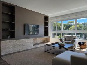 a living room with a fireplace and a tv on a wall at Apartamentos Altos da Bela Vista by Achei Gramado in Gramado
