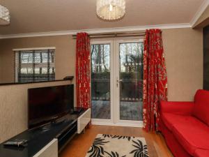 a living room with a red couch and a large window at Swinsty Lodge in Harrogate