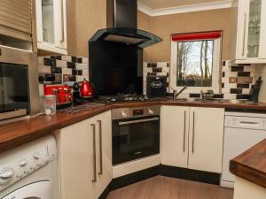 a kitchen with white cabinets and a stove top oven at Swinsty Lodge in Harrogate