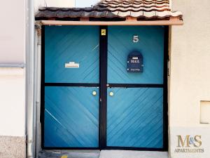 een blauwe deur op een gebouw met een bord erop bij Anja Apartman in Novi Sad