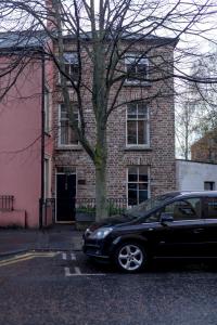 a black car parked in front of a brick building at Belfast City self catering 3 bedroom town house in Belfast