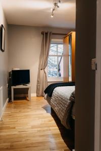 a bedroom with a bed and a television and a window at Belfast City self catering 3 bedroom town house in Belfast
