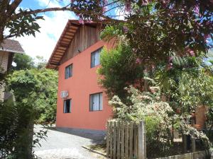 an orange house with a fence in front of it at Hostel Dina & Suítes in Pomerode