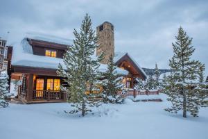 a house in the snow with trees in front of it at Western Tanager Cabin in Big Sky