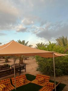 an orange umbrella and chairs under a table at Almazham holiday house in Al-ʿUla