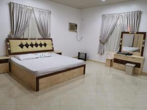 a bedroom with a large bed and a mirror at Almazham holiday house in AlUla