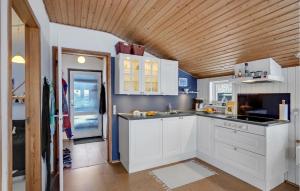 a kitchen with white cabinets and a wooden ceiling at 2 Bedroom Awesome Home In Thyholm in Thyholm